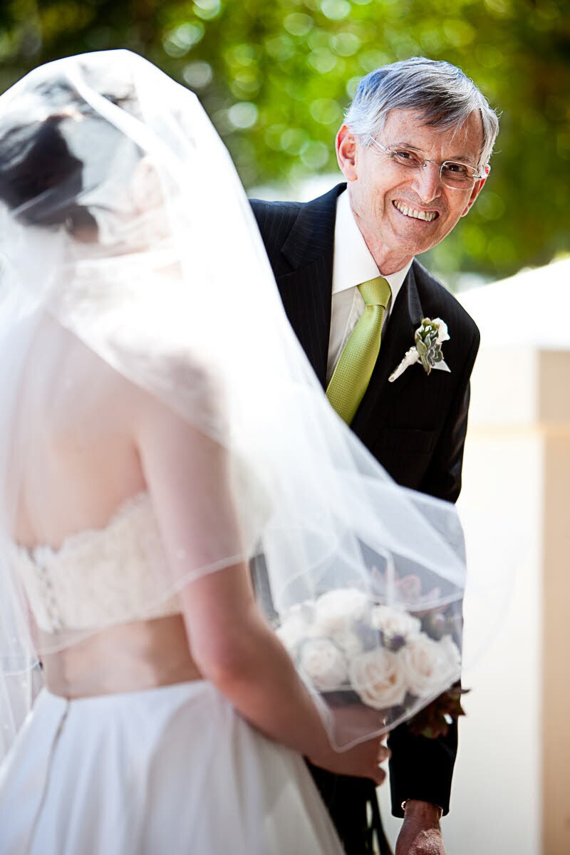 Father of bride wearing peeking from around bride - photo by South Africa based wedding photographer Greg Lumley
